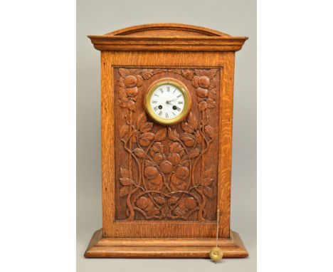 AN ARTS &amp; CRAFTS OAK CASED MANTEL CLOCK, the domed top above a rectangular case carved with entwined foliage and fruits, 