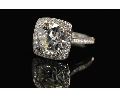 A STUNNING MODERN LARGE DIAMOND RING, centring on a transitional round brilliant cut diamond, enclosed within a pave diamond 