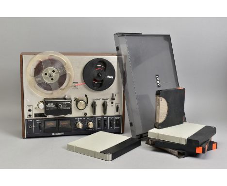 AN AKAI 4000DB VINTAGE REEL TO REEL RECORDER, with a walnut effect outer casing and damaged smoked plexi glass front cover wi