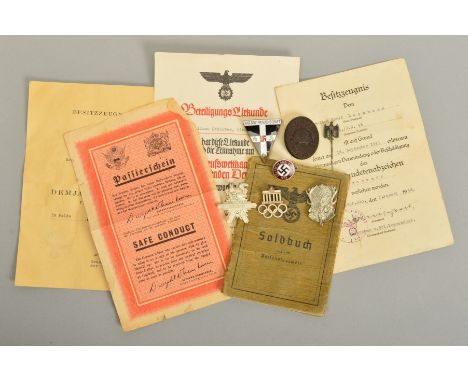 A NUMBER OF GERMAN WWII 3RD REICH MILITARY BADGES AND PAPERWORK, comprising of soldiers 'Soldbuch' 2 x 'Besitzzeugnis Award' 