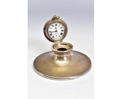 AN EDWARDIAN SILVER CAPSTAN INKWELL, the hinged cover fitted with a top wind pocket watch, the white enamel dial with Roman n