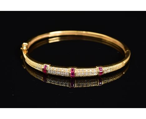 A MODERN 18CT GOLD, RUBY AND DIAMOND HALF HOOP BANGLE, an oval hinged bangle fitted to tongue and box style clasp, estimated 