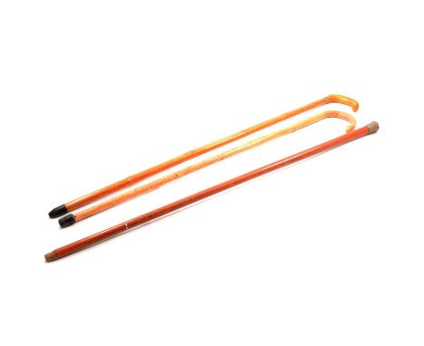 Naive carved hardwood walking stick, the pommel with primitive carved head design, 81cm; two walking canes with white metal p