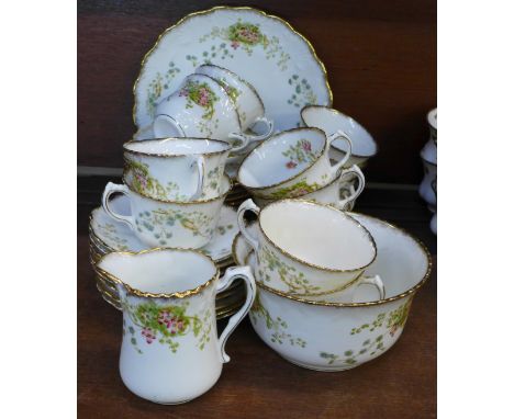 An early 20th Century floral decorated tea service, 12 cups (two a/f), 11 saucers, 12 side plates, (one a/f), cream, sugar an