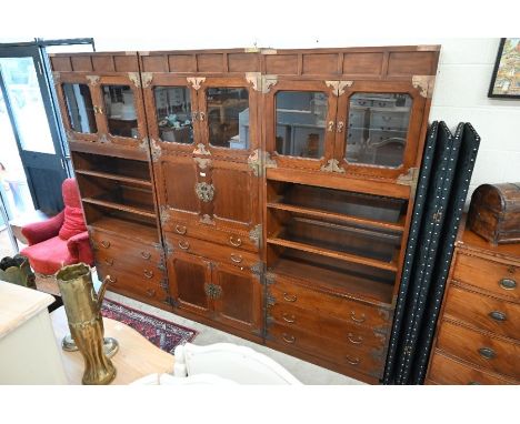 A six section Chinese brass mounted hardwood wall unit, comprising open shelves, glazed cabinets, cabinets and centred by a m