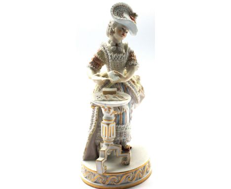 A late 19th century Meissen porcelain figure of a lady card dealer standing in front of a tripod table with playing cards in 