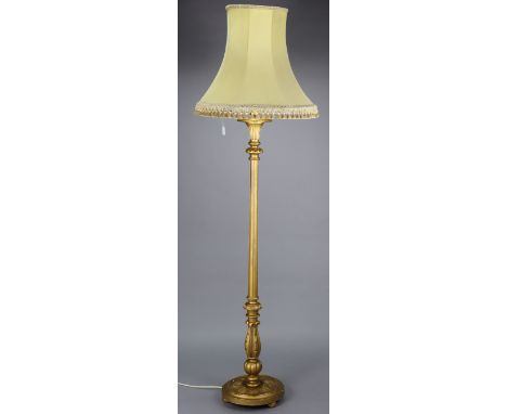 A gilt painted wooden standard lamp with a fluted &amp; vase-turned centre column, &amp; on a circular base, with shade.
