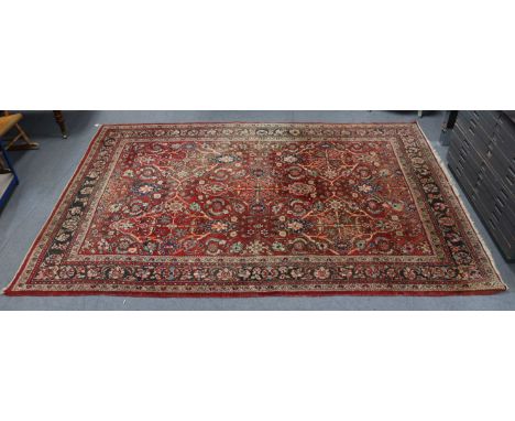 A Persian pattern small carpet of madder &amp; ivory ground with all-over repeating multi-coloured geometric design to centre