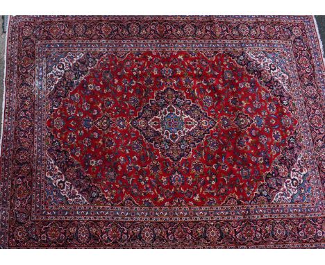 A fine Kashan Carpet, Central Persia, The madder field of scrolling floral vines centred by an indigo medallion framed by ivo