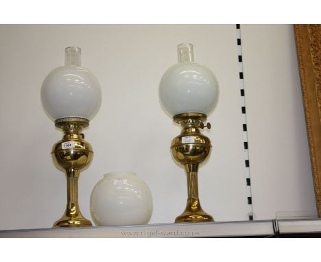 A pair of Brass Oil Lamps with clear glass chimneys and white glass globe lamp shades, with spare shade, 22 1/2'' tall.