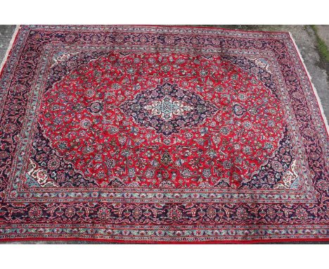 A Kashan Carpet, Central Persia, the madder field of angular vines centred by an indigo flowerhead medallion framed by ivory 