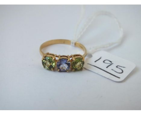 An 18ct gold ring set with 2 peridot stones and 1 amethyst stone - marked 750 - size N/O - 2.4gms