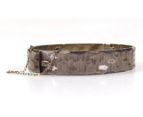 A silver bangle, with engraved design, hinge clasp, and safety chain, 35.5g. 