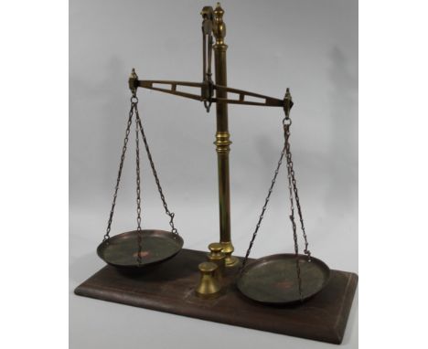 An early 20thC tabletop brass scale, on mahogany stand with circular trays and two brass weights, one marked five silver, the