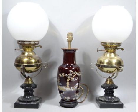 A pair of Victorian style brass oil lamps, each with milk glass shades, bulbous reservoir and inverted stems, with electrical