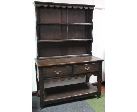 An 18thC style oak dresser, of small proportion, the upper section with a fixed carved cornice revealing Delft racks, the sub