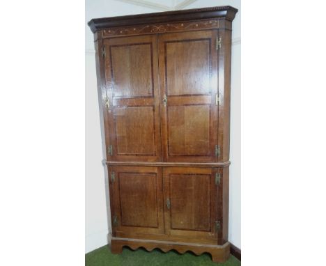 A late 18thC oak and mahogany freestanding corner cupboard, with a double upper dentil cornice raised above an inlaid section