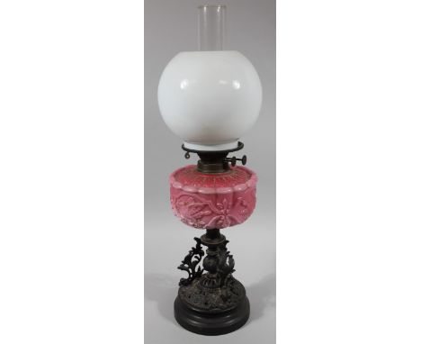 A late Victorian oil lamp, with milk glass orb shade, clear glass funnel and pink glass reservoir on an elaborate metal stem 