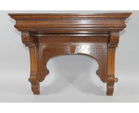A late 19thC oak aesthetic wall shelf, with overhanging moulded top set with dentil frieze raised on scroll supports with car