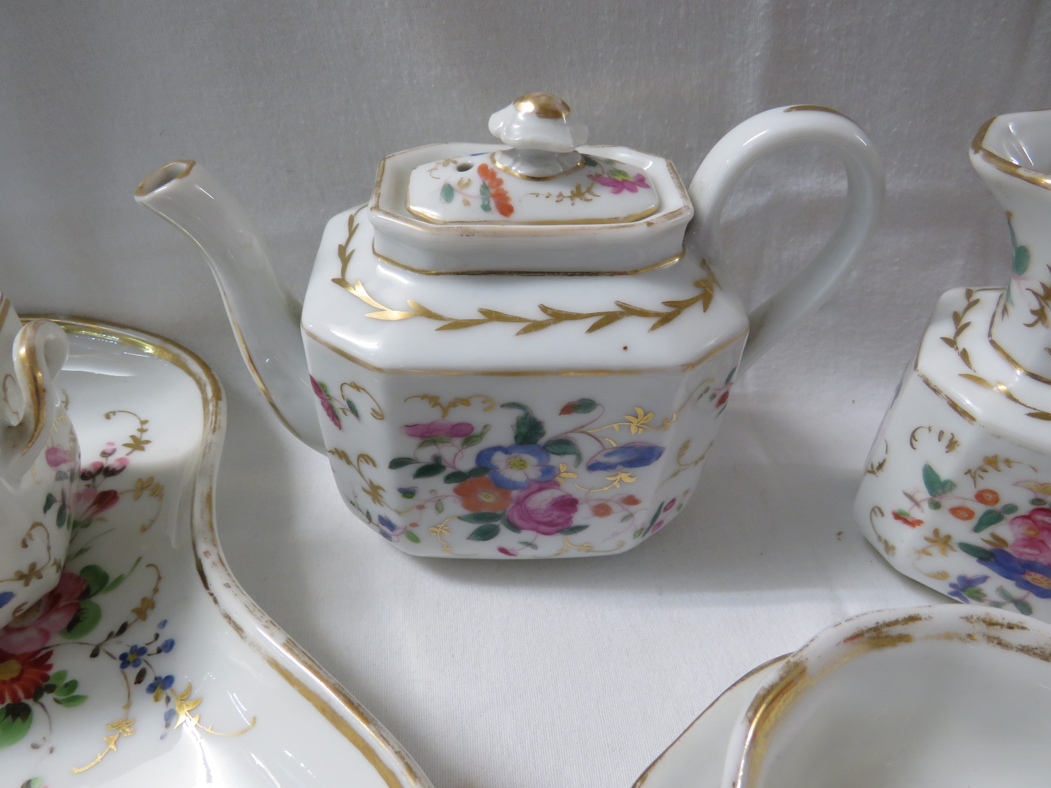 A white porcelain tea set hand painted with flowers and gilding