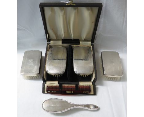 A cased set of two engine turned clothes brushes, Birmingham 1922, together with comb and two sterling silver backed brushes 