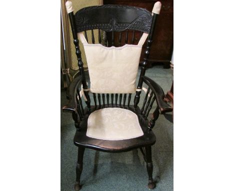 A late 19th century ebonised mahogany spindle back armchair, the backboard carved with acanthus leaves, with a more recently 