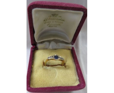 Yellow metal ring set with solitaire sapphire between a line of six small white stones, the shank stamped 18CT, ring size L/M
