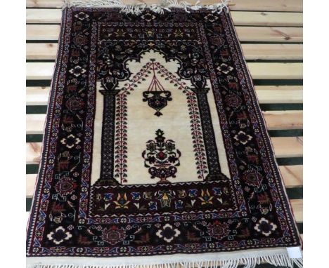 A modern red and cream ground machine woven prayer rug with motif of lamp and vase (112cm x 76cm)