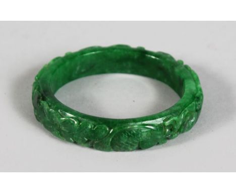 A CARVED CHINESE APPLE GREEN JADE BANGLE.