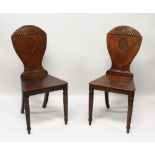 A GOOD PAIR OF REGENCY MAHOGANY HALL CHAIRS, with shaped backs, solid seats, on turned and