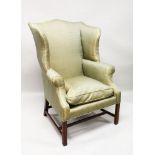 A GEORGE III MAHOGANY WING ARMCHAIR, with padded back, arms and seat, supported on square legs.