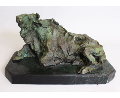 AN ABSTRACT BRONZE OF A COW LYING DOWN. 1ft 4ins.