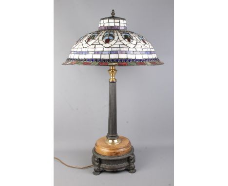 A large Tiffany style table light, with Corinthian style column mounted on wooden base, raised on metal plinth.  Working, som