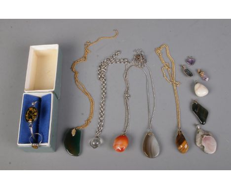 A collection of assorted gem stone pendants and necklaces including tigers eye, amethyst, carnelian, agate, crystal orb on si