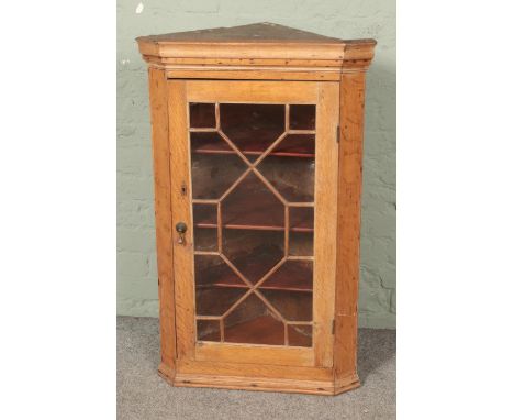 A light oak corner cabinet with glazed door.Hx102cmWx62cmDx38cm  