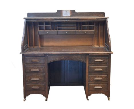 Early 20th Century stained oak roll top desk, the tambour front enclosing a drawered and pigeon holed interior, the base with