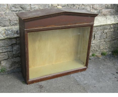 A Victorian pine wall mounted shop display cabinet with glazed panelled front, set beneath an architectural pediment with gla