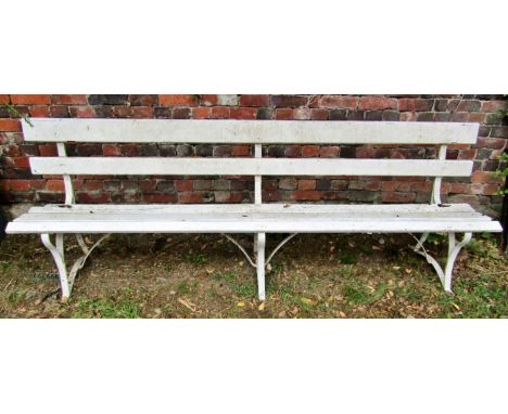 A vintage bench with painted wooden lathes, raised on sprung steel supports, 244cm long (af) 