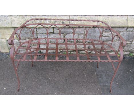 A weathered ironwork two seat garden bench with strapwork seat, twisted rails, and open arched back, 116cm wide 