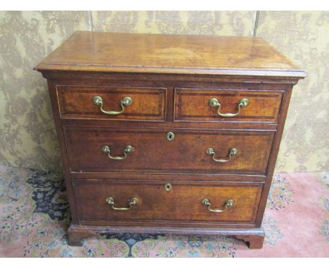 A small Georgian oak chest of two long and two short drawer, crossbanded in walnut on bracket supports with brass fittings, 8