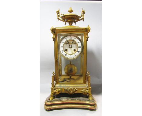 A Victorian four pane mantle clock, the gilded brass case enclosing an eight day striking mechanism, with visible escapement,