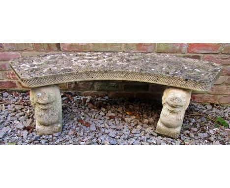 A weathered three section composition stone garden bench with crescent shaped seat raised on winged lion supports, 144cm wide