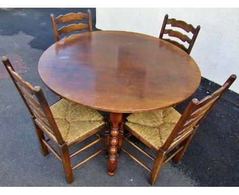 An old English style oak dining table the circular top raised on bobbin supports united by a matching X shaped stretcher, 122