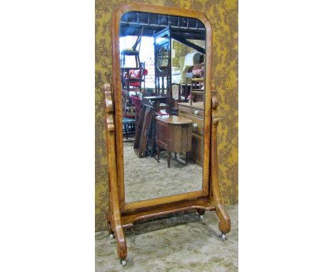A Victorian pine cheval mirror with simple arched frame raised on chamfered swept scrolled and pierced supports with white ce
