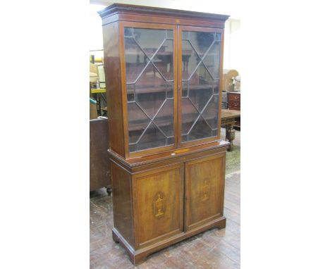 An Edwardian inlaid mahogany glazed bookcase cabinet, the dentil moulded cornice over a pair of geometric moulded glazed pane