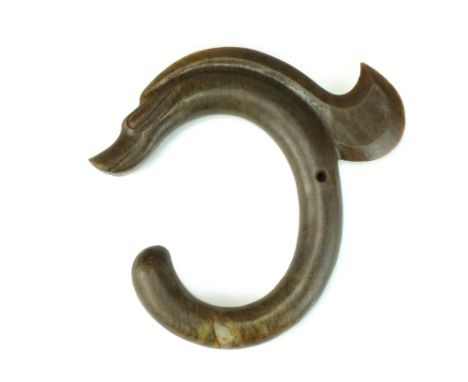 A Chinese archaistic jade carving, Hongshan style, the mid green stone with brown veining carved as a coiled crested dragon, 