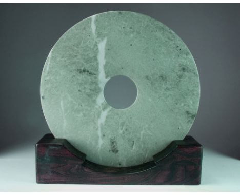 A very large Chinese jade Bi disc, 20th century, the pale green stone with white and darker green mottling carved as a plain 