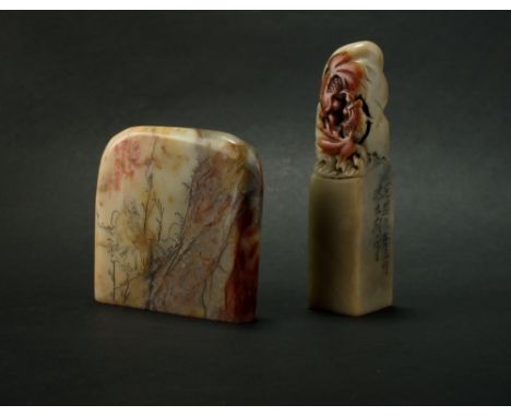 Two Chinese grey and red soapstone seals, Qing, the first carved with a lotus spray, 9.5cm high, the second of pebble form an