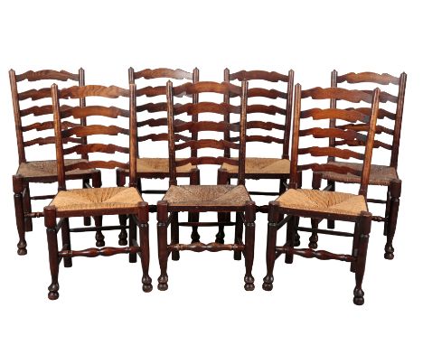 A MATCHED SET OF SEVEN LADDER BACK DINING CHAIRS with square rush seats, on turned legs and stretchers, with pad feet, 100cm 