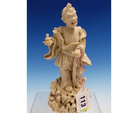 A BLANC DE CHINE FIGURE OF LIDIEHGUEI STANDING ON A ROCKY MOUND WITH A WALKING STICK IN HIS LEFT HAND AND A GOURD IN HIS RIGH